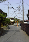 A nice and quiet place in the labyrinth of small streets in Tsujido, there is someone riding a bike, nice trees and lots of wires.