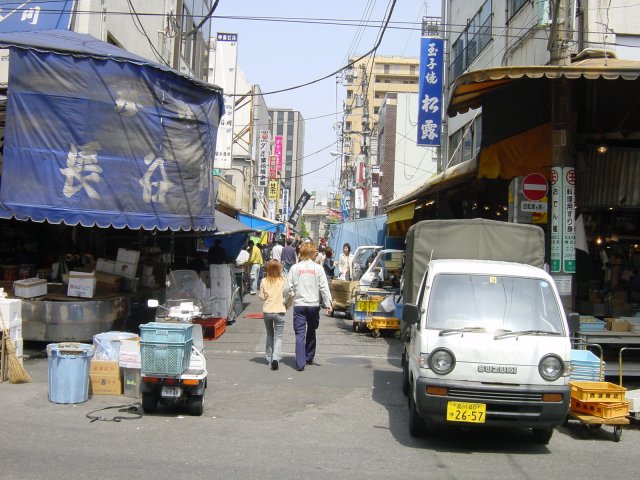 Magasins de produits de la mer, petites voitures de livraisons et quelques visiteurs a Tsukiji, Tokyo, Japon.