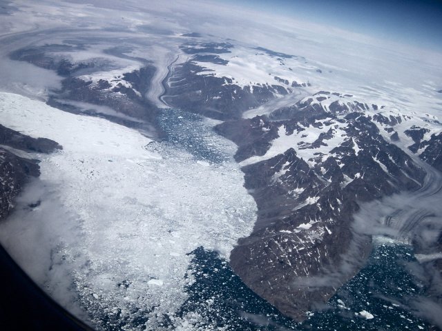 Un fjord sur la cote Groenlandaise avec les glaciers se jetant dans la mer et une sorte de banquise d'ou se detachent des icebergs.